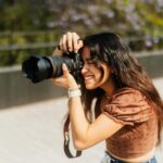 ragazza che fotografa all’aperto con una reflex canon in pieno giorno