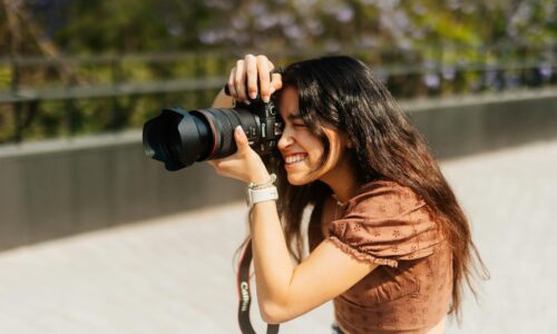 ragazza che fotografa all’aperto con una reflex canon in pieno giorno