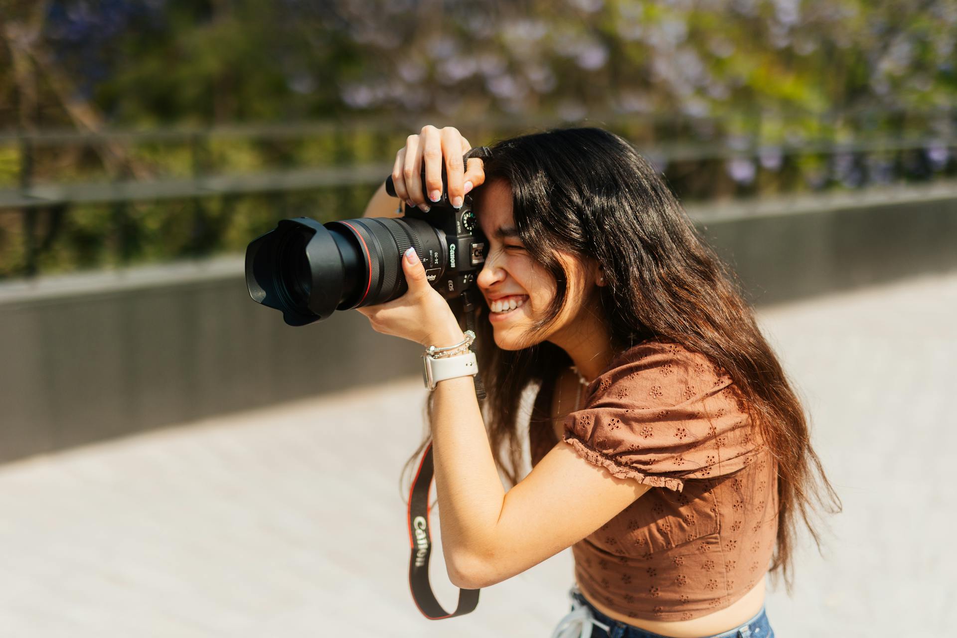 ragazza che fotografa all’aperto con una reflex canon in pieno giorno