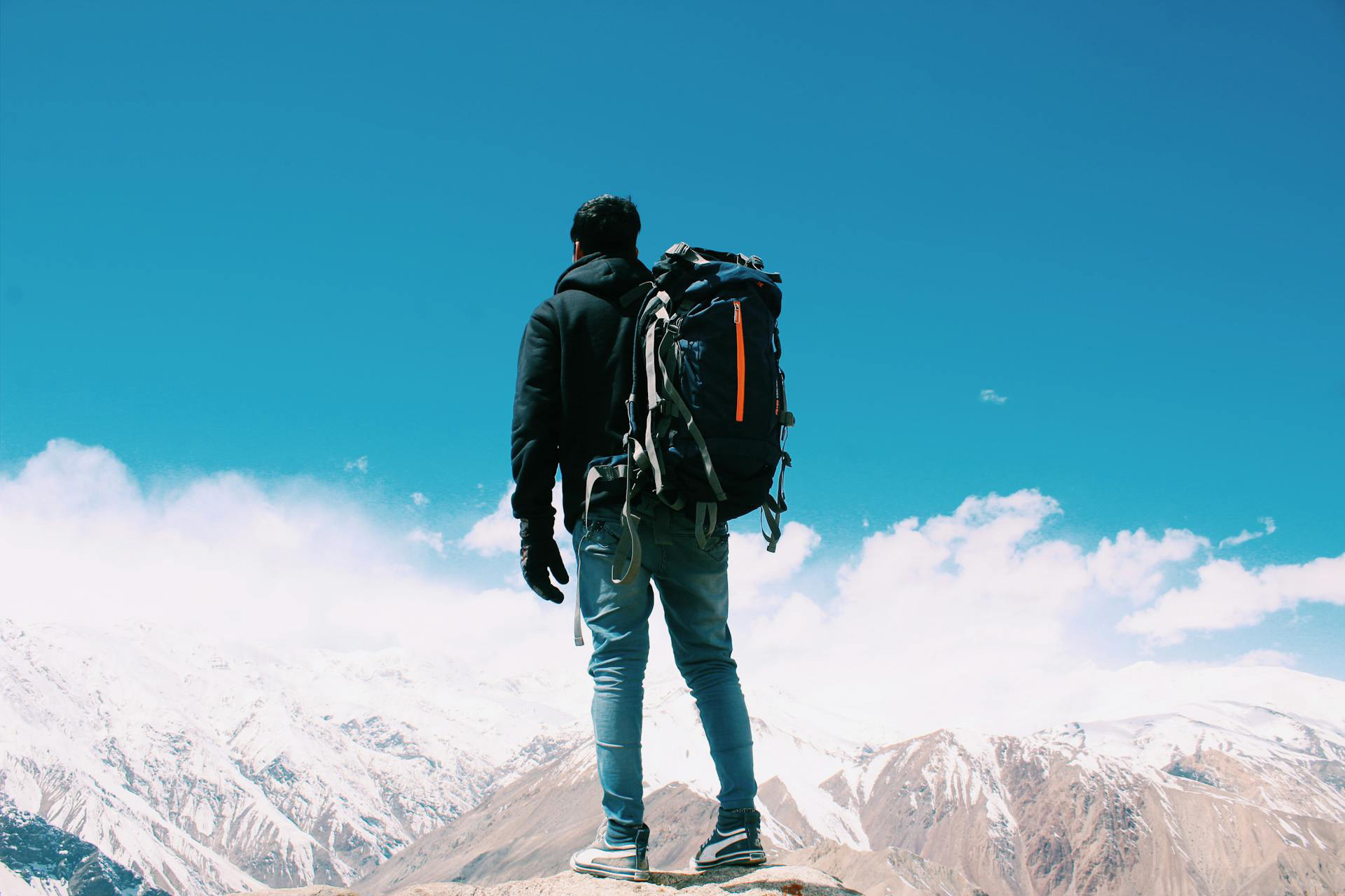 Escursionista di spalle con zaino da trekking su cima montuosa innevata