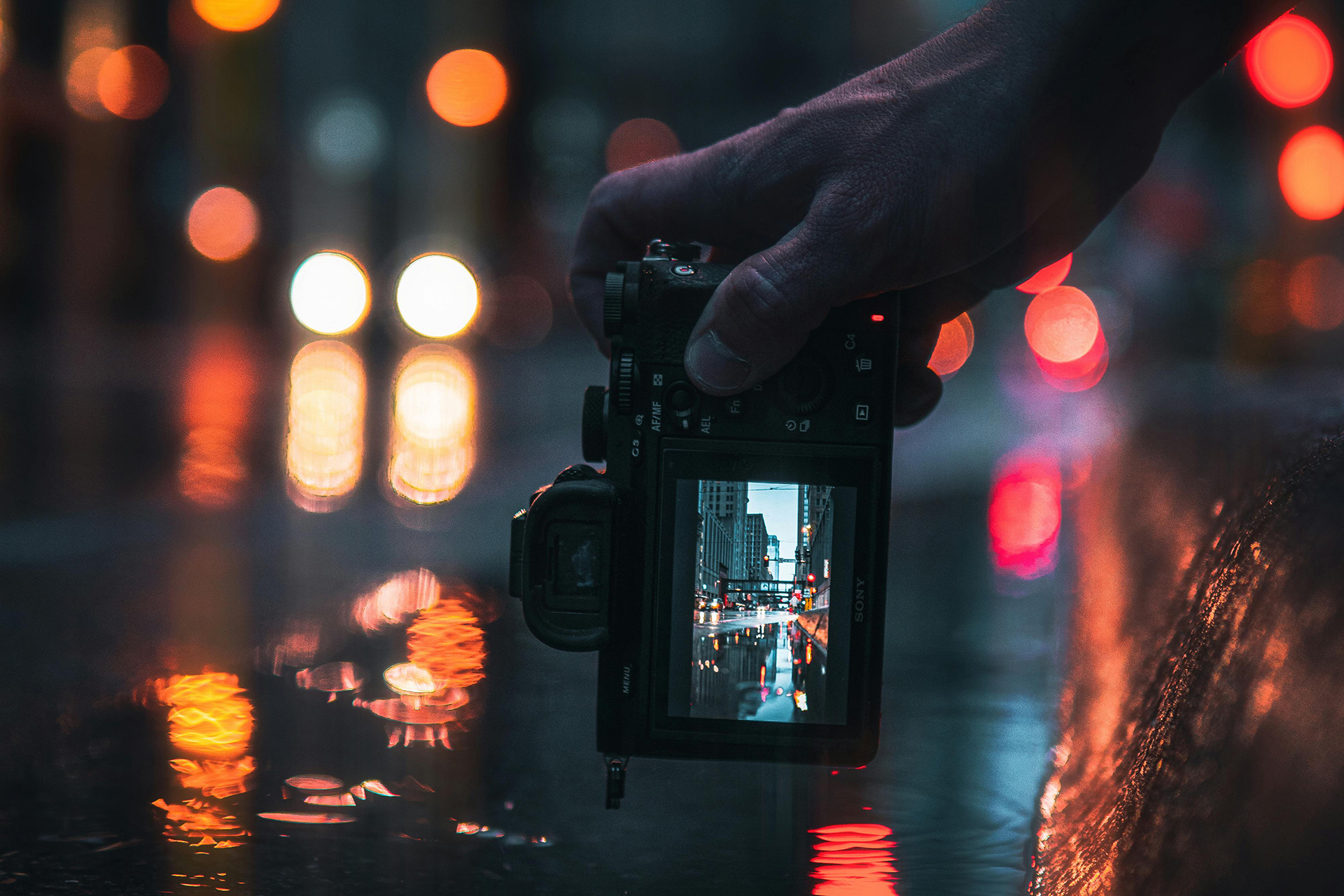 Ragazzo con fotocamera mirrorless Sony Alpha che scatta una foto di strada notturna
