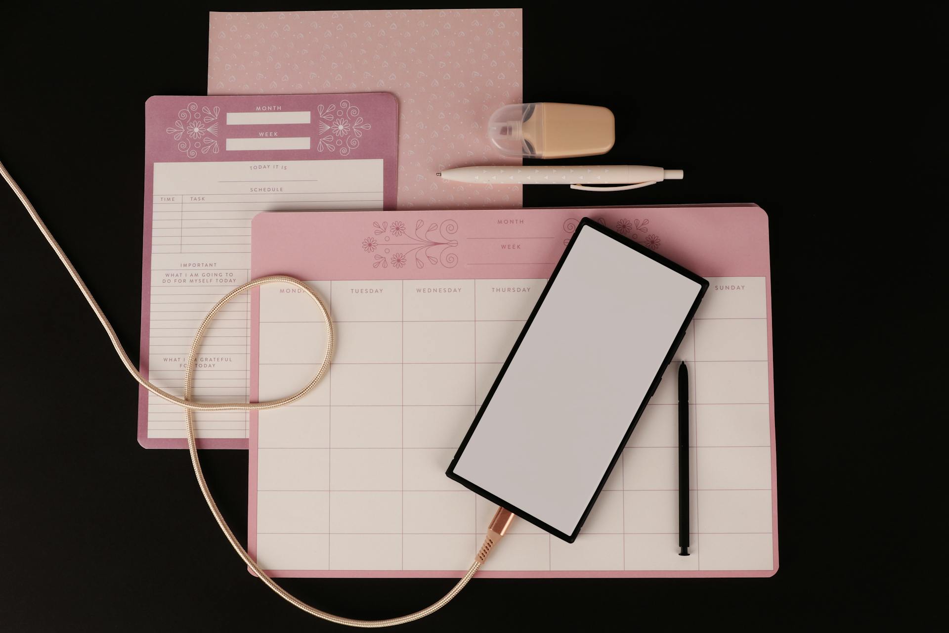 Scrivania minimalista con tastiera rosa, tablet e strumenti di pianificazione creativa