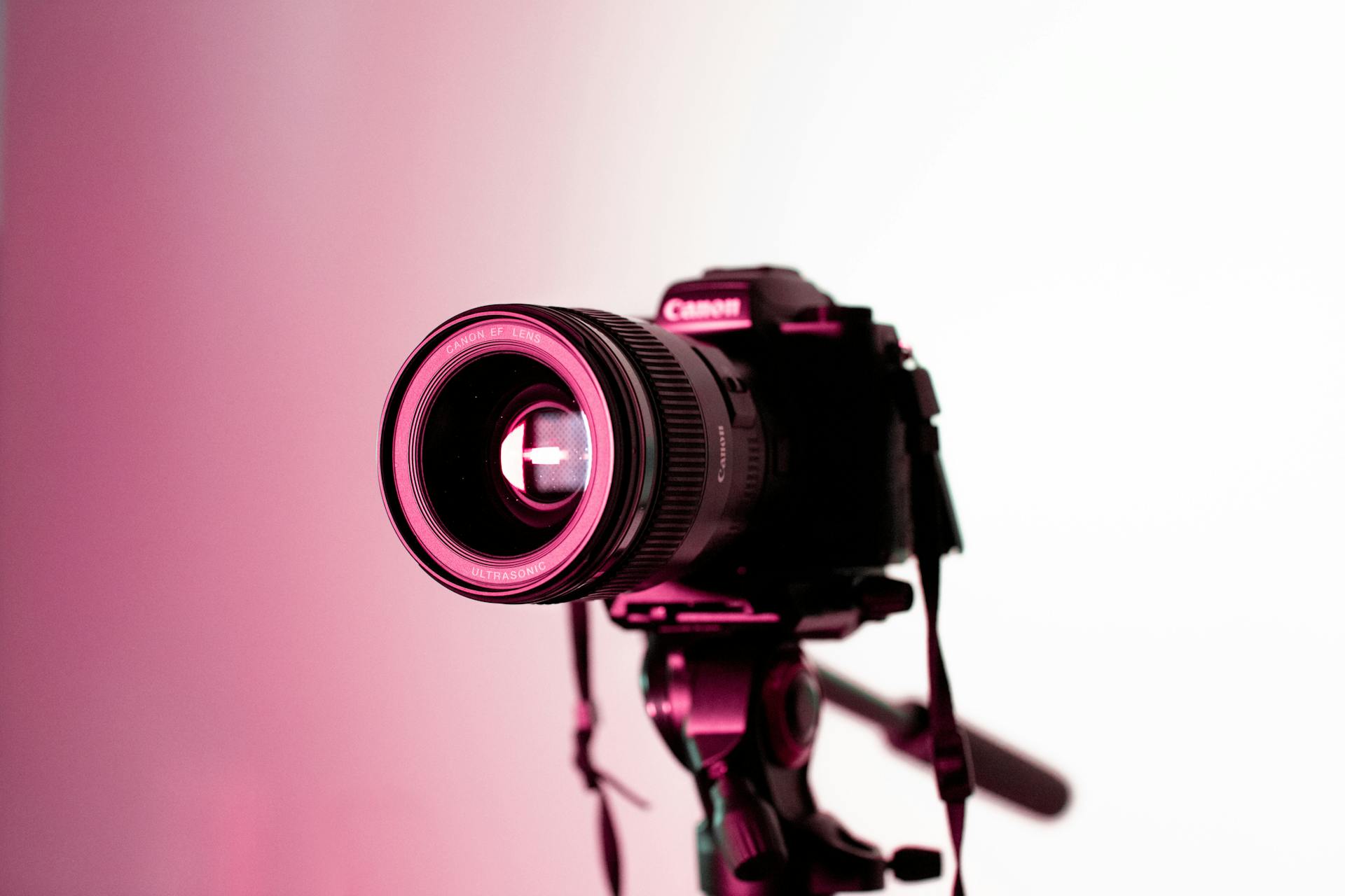 Fotocamera reflex Canon su treppiede con illuminazione neon rosa in ambiente creativo