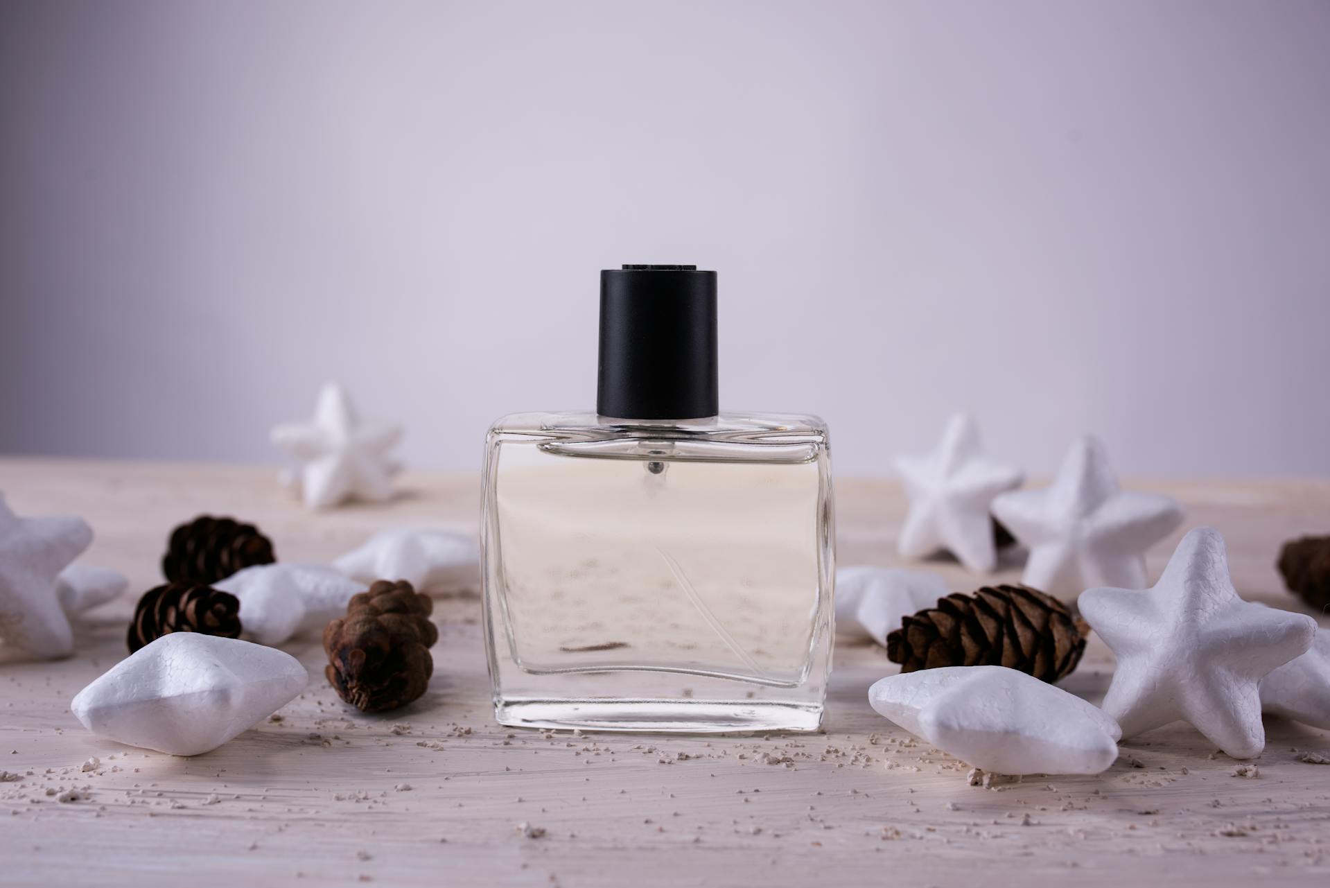 Flacone di profumo in vetro trasparente con tappo nero in composizione di still life su legno