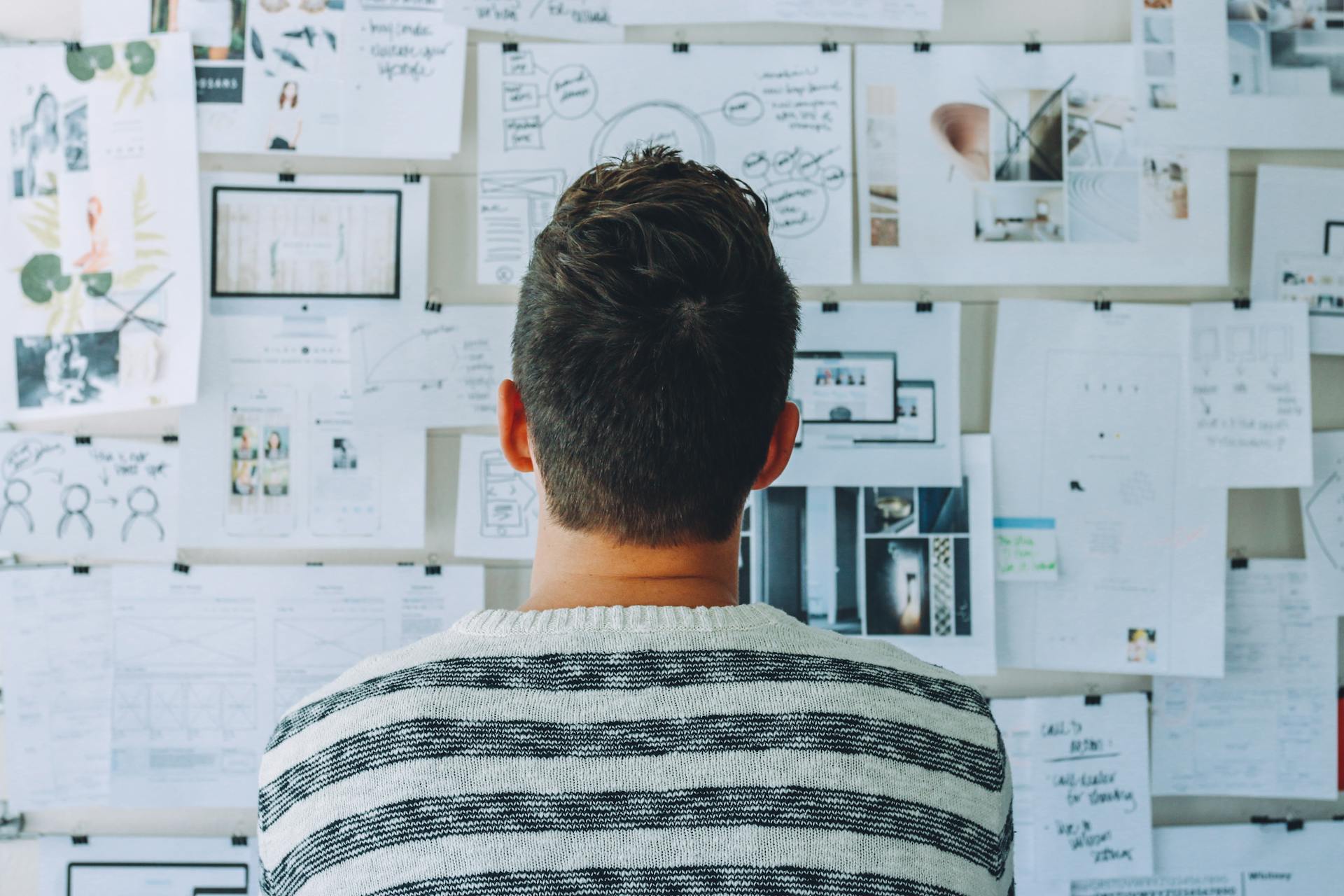 Professionista al lavoro con grafici, wireframe e diagrammi su parete per project management e UX design