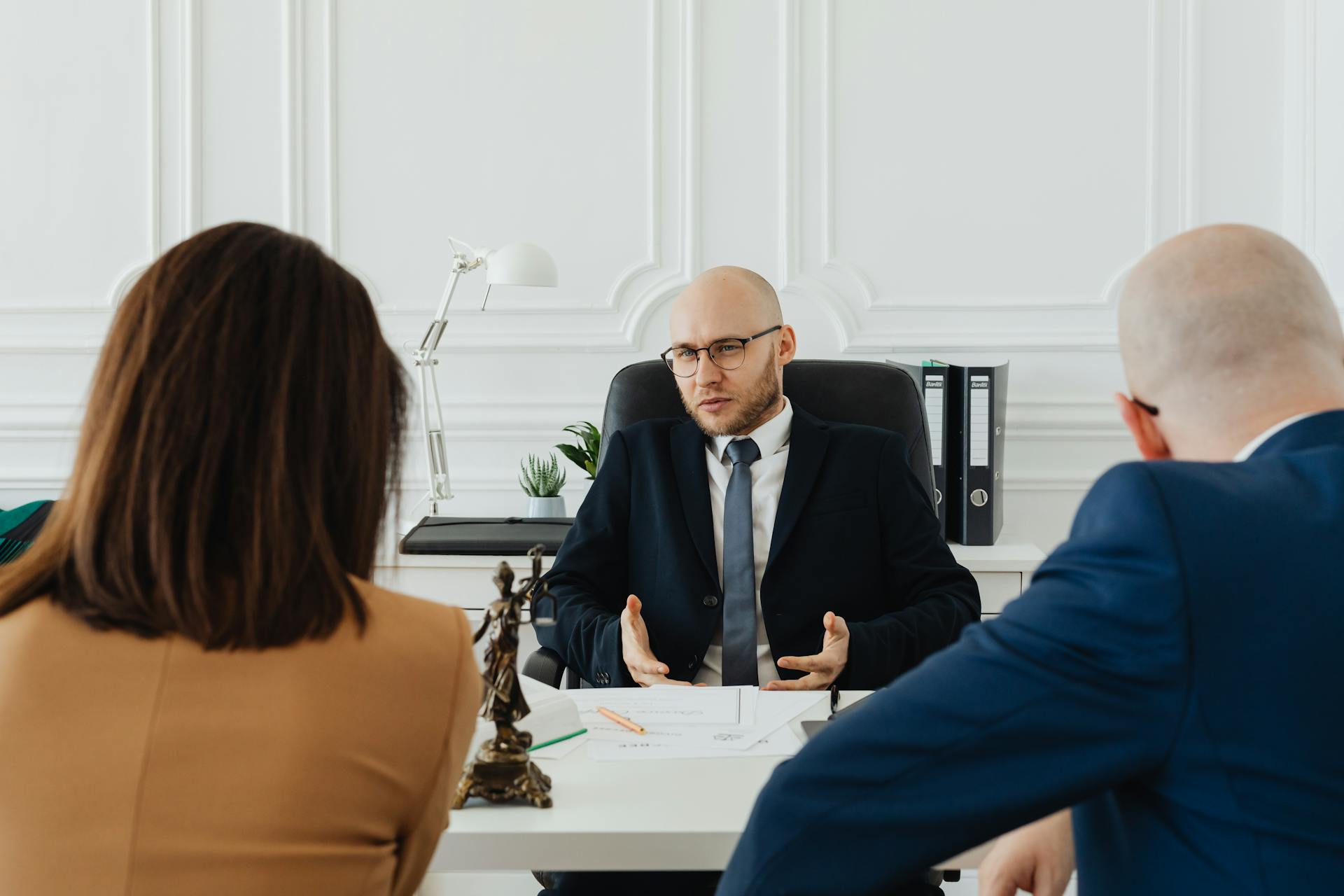 Incontro in ufficio tra professionista legale e clienti con revisione documenti e consulenza