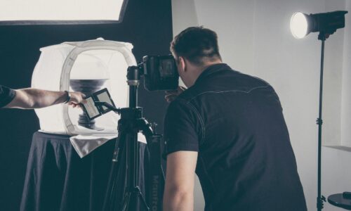 Fotografo in studio impegnato in una sessione di still life con set luci professionali e attrezzatura da studio