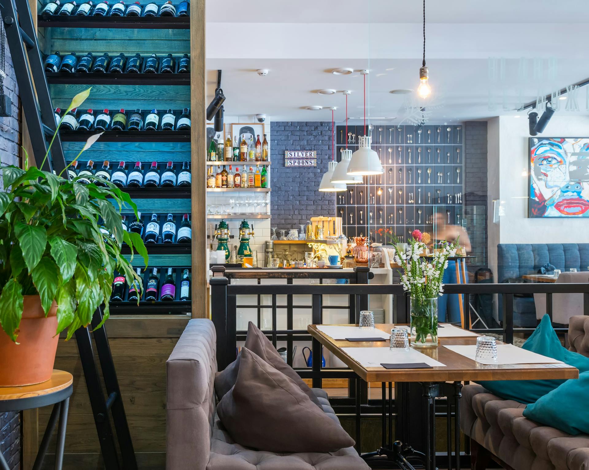 Interno moderno di ristorante elegante con tavoli in legno, divanetti e parete vini retroilluminata