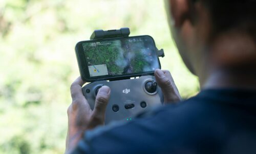 Pilota di drone che controlla un dispositivo DJI con smartphone durante un volo aereo