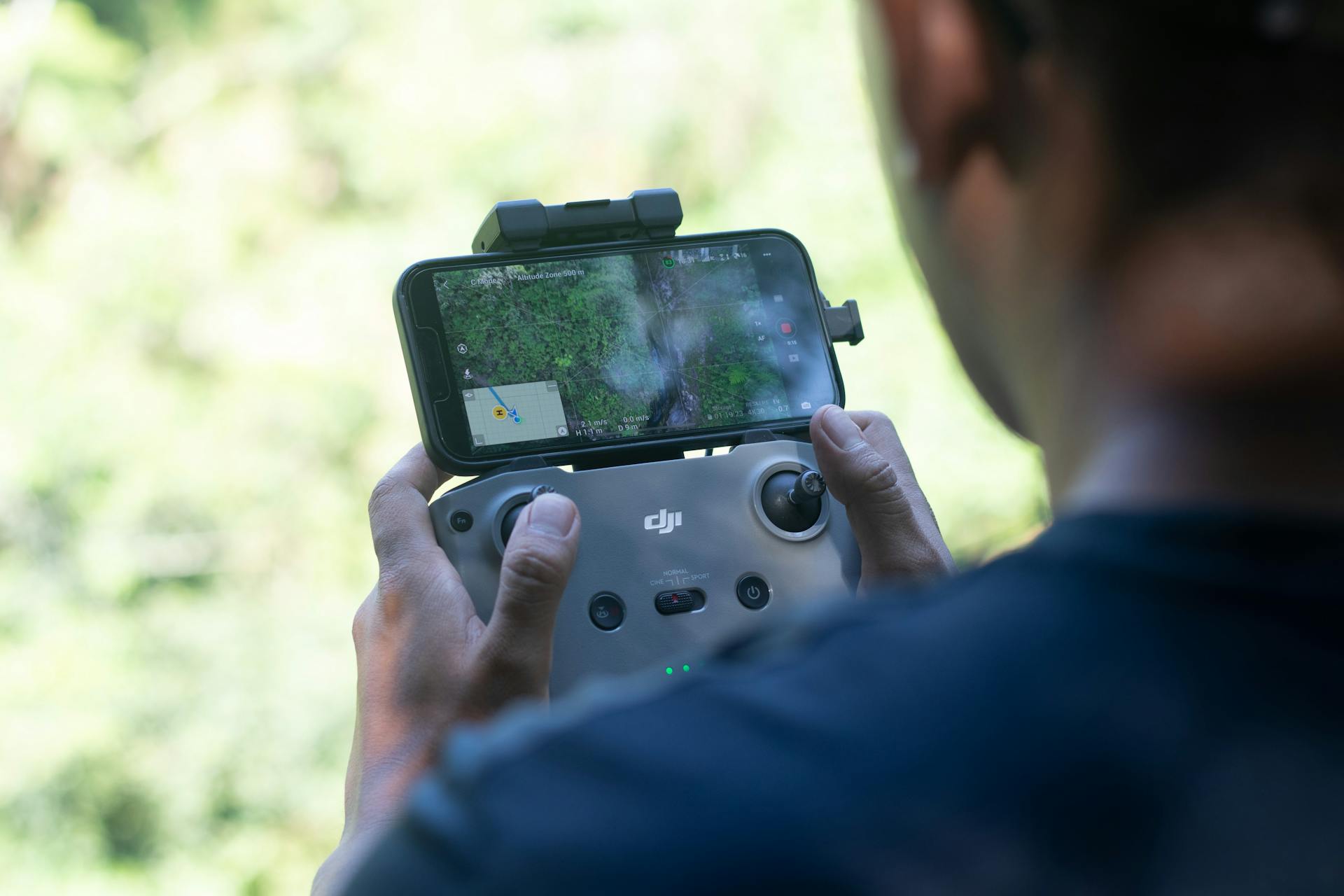Pilota di drone che controlla un dispositivo DJI con smartphone durante un volo aereo
