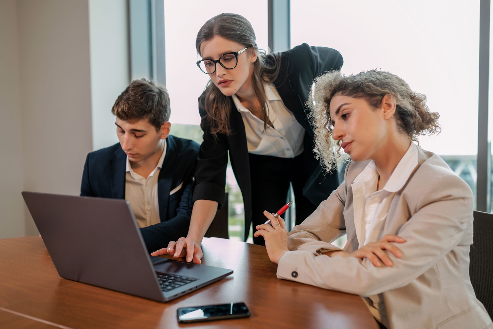 Tre colleghi di lavoro analizzano insieme i dati su un computer portatile in ufficio