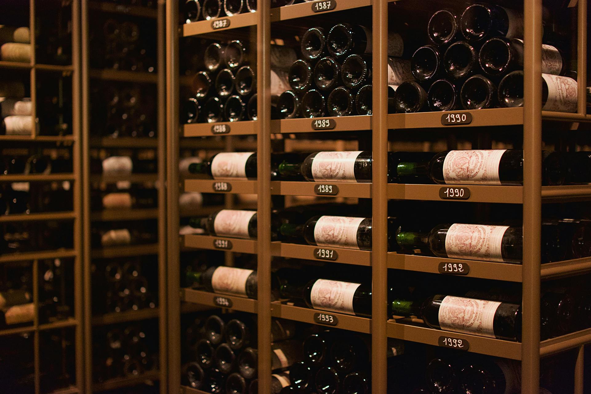 Bottiglie di vino pregiato disposte in modo ordinato all'interno di una cantina storica di Minervino Murge.
