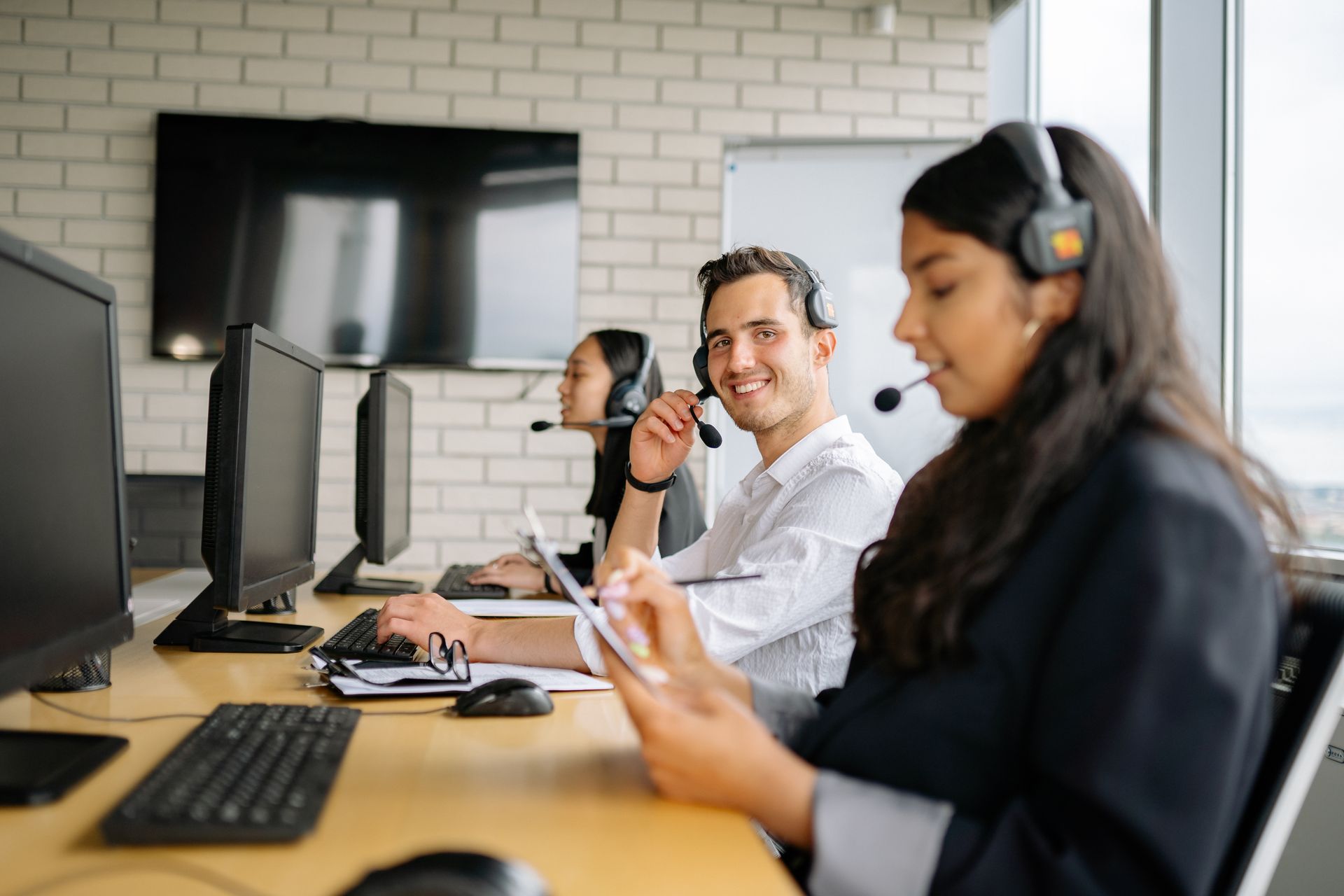 Operatori di un call center aziendale con cuffie e computer che lavorano in ufficio per i servizi digitali.