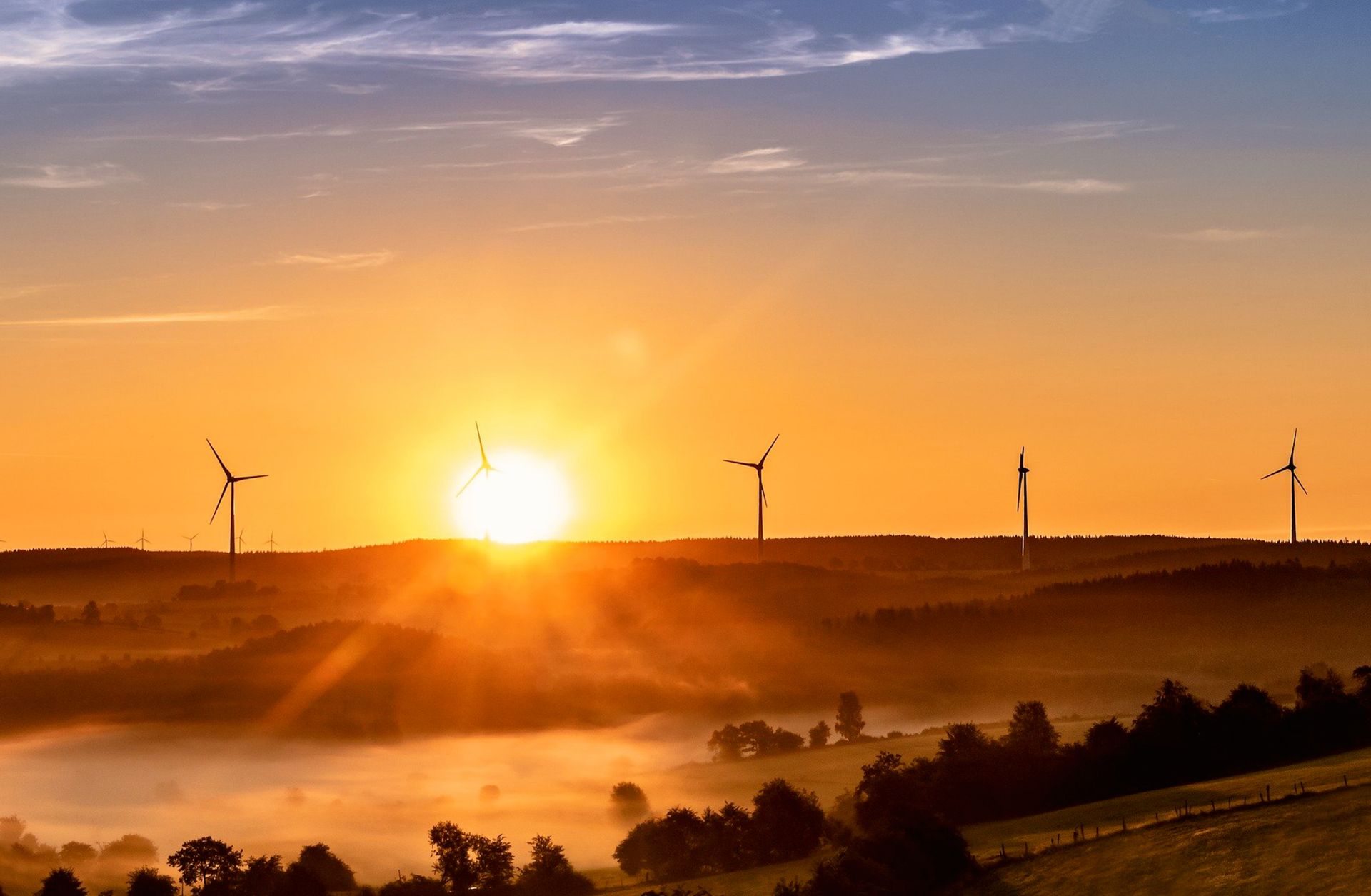 Pale eoliche al tramonto in un paesaggio collinare della BAT per la comunicazione delle energie rinnovabili