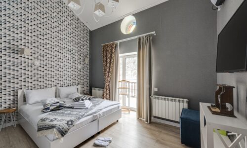 Camera da letto matrimoniale moderna e luminosa di un hotel di design con letto rifatto e finestra sul balcone