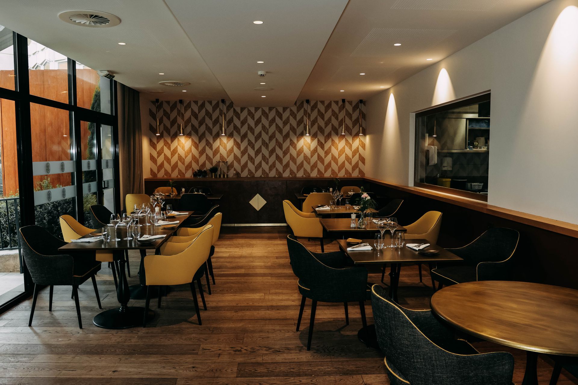 Foto di una sala ristorante elegante e moderna con tavoli in legno e poltroncine gialle e grigie per la comunicazione e il marketing della ristorazione e ricezione alberghiera nella BAT.