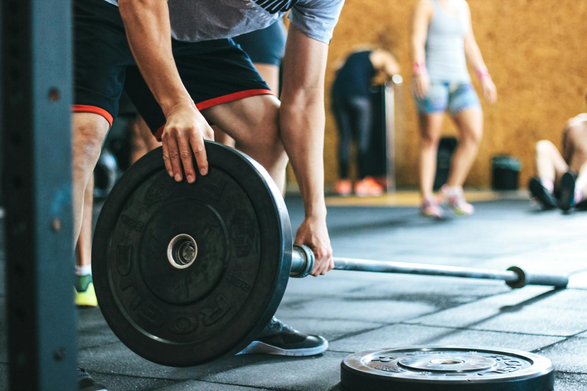 Bilanciere con dischi pesanti su pavimento di una palestra durante un allenamento di crossfit.