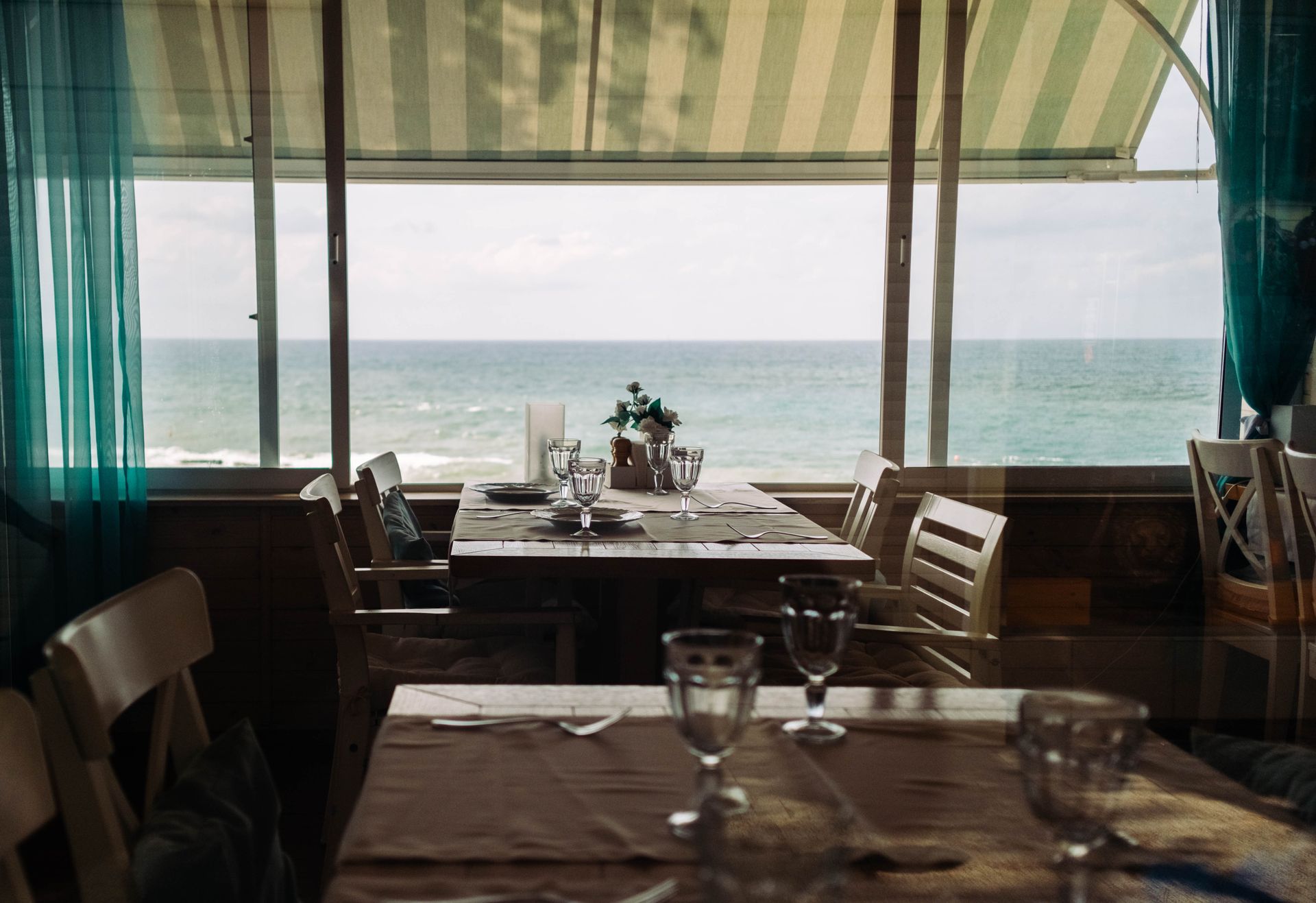 Tavolo apparecchiato in un ristorante sul mare visto attraverso una grande finestra