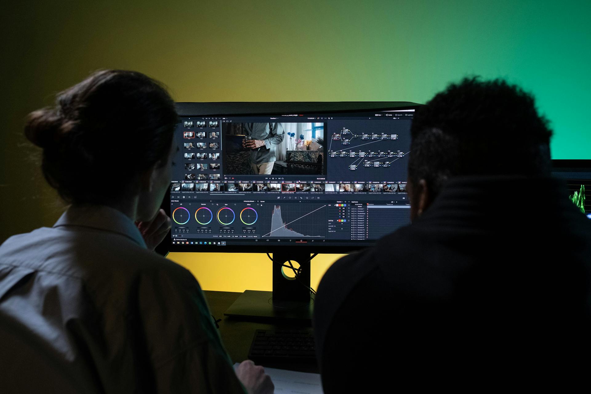 Due professionisti del video editing analizzano e correggono il colore di un filmato sul monitor di una workstation all interno di uno studio di post produzione cinematografica
