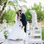 Sposi che si baciano durante una cerimonia di matrimonio all'aperto a Trani con addobbi floreali bianchi